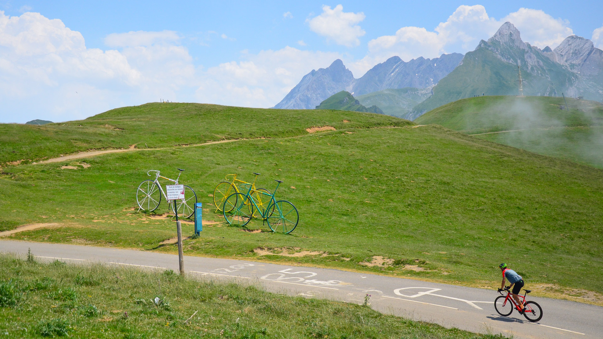 un cycliste arrive en danseuse en haut d'un col