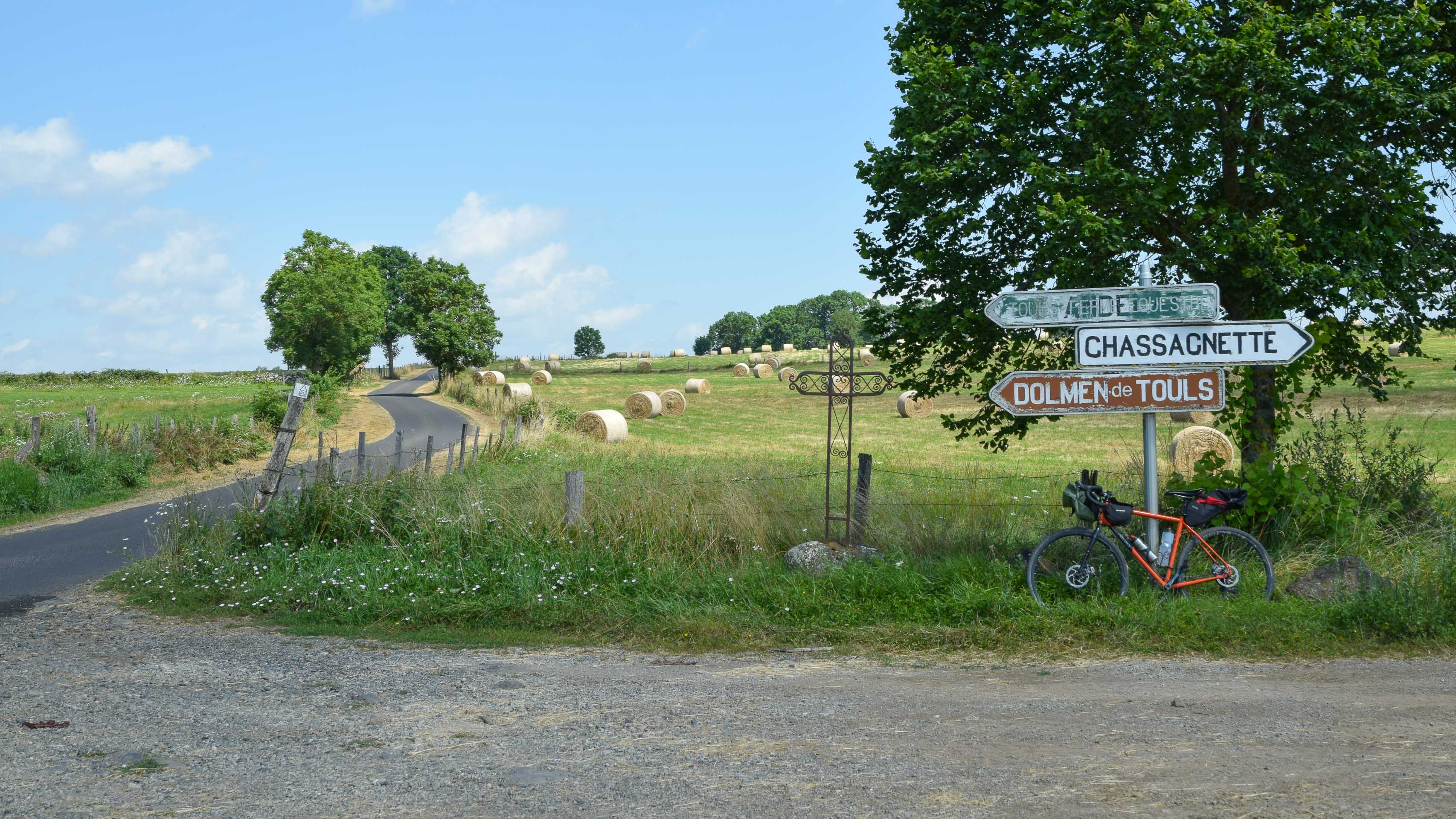 vélo gravel posé sur les panneaux d'intersection à promixité des Dolmens de Touls dans le Cantal