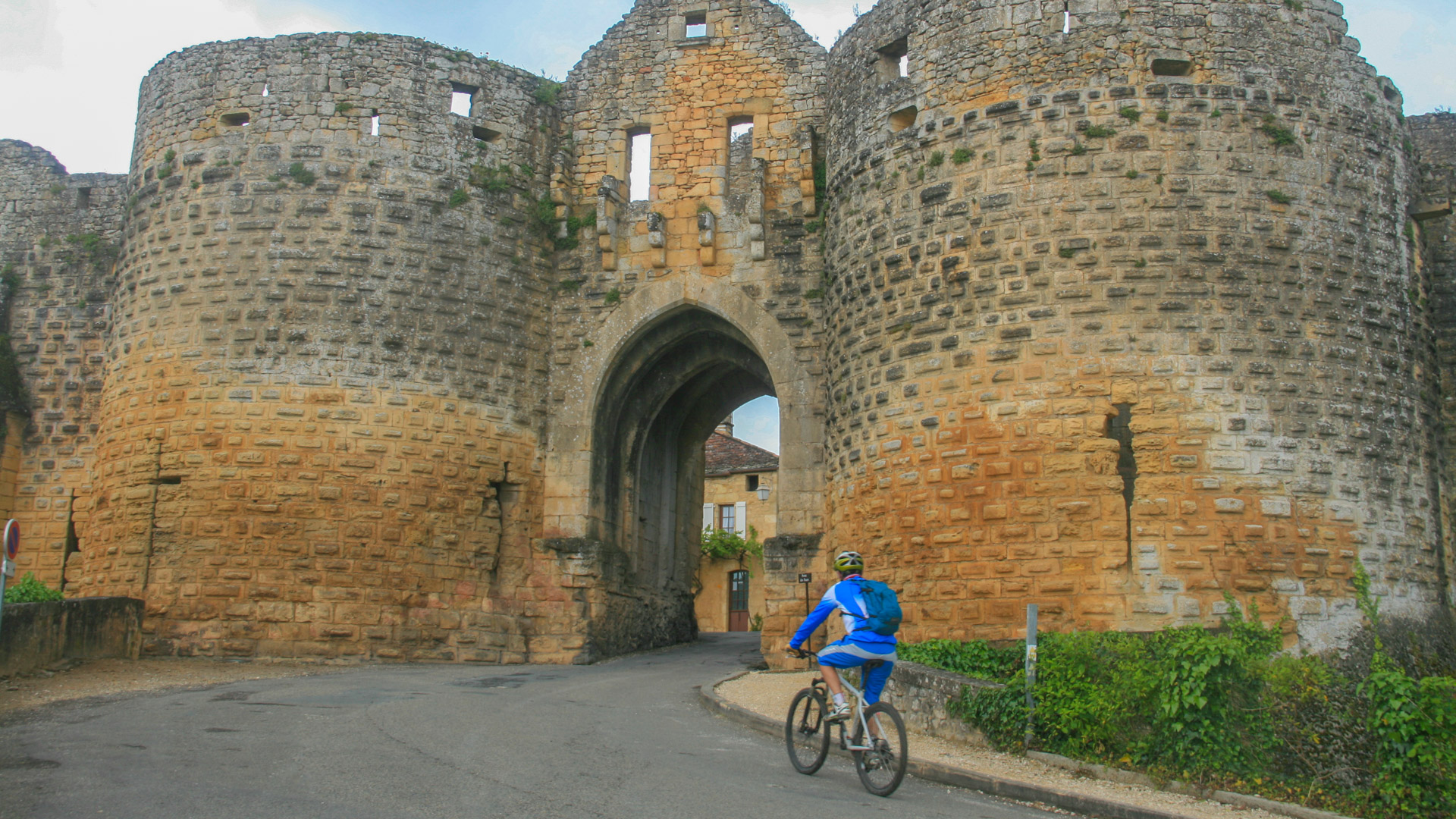 homme à VTT entre dans le village médiéval de Domme