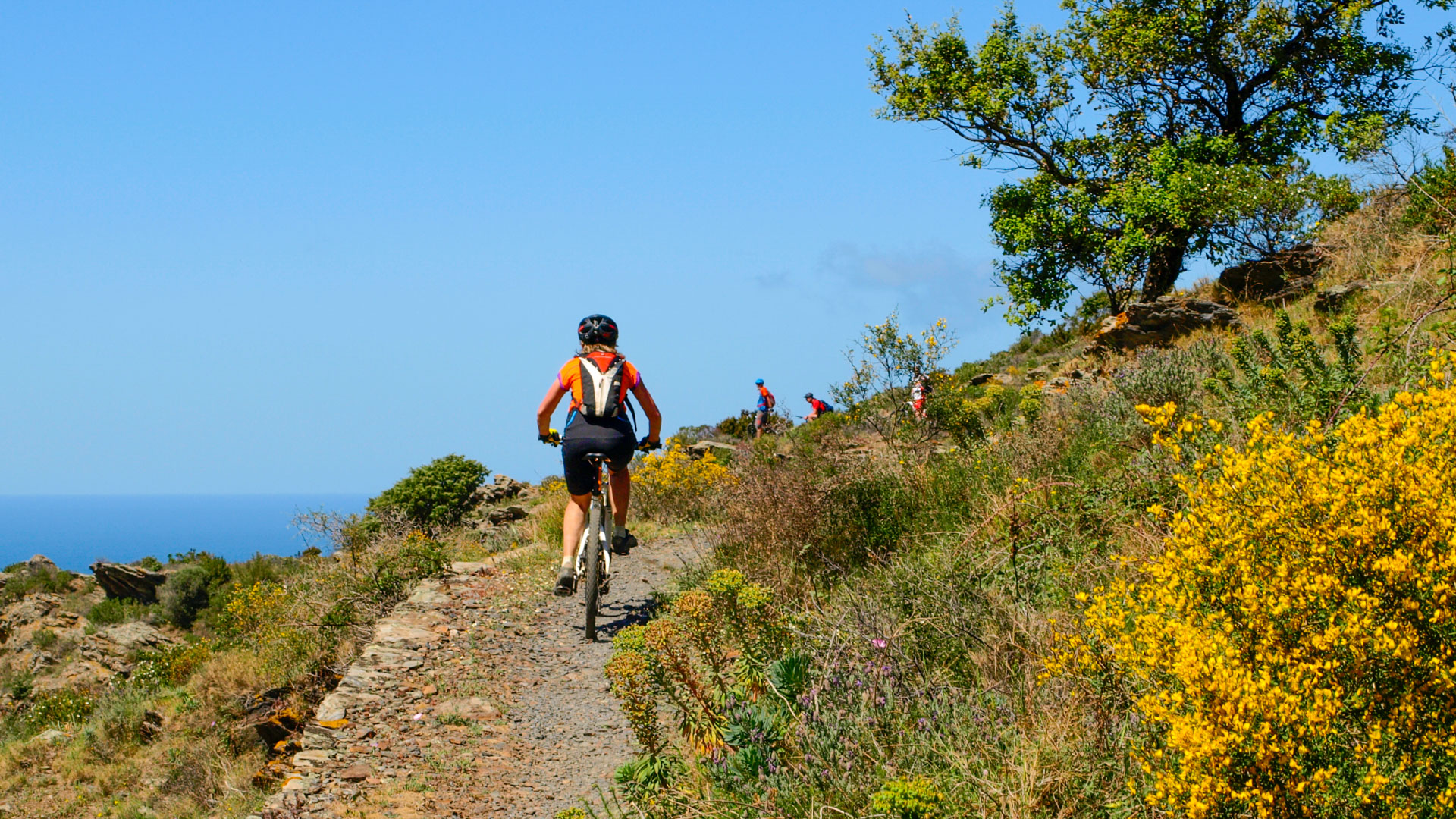 femme à vtt sur un chemin en balcon sur la campagne catalane et la mer