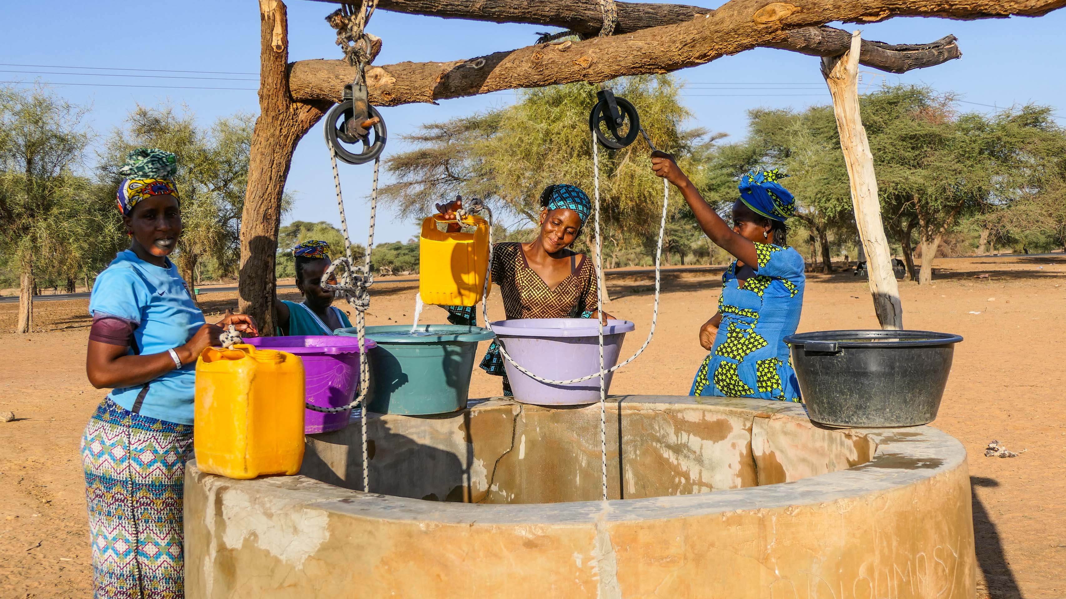 cycliste et femme sénégalaise autour d'un puit