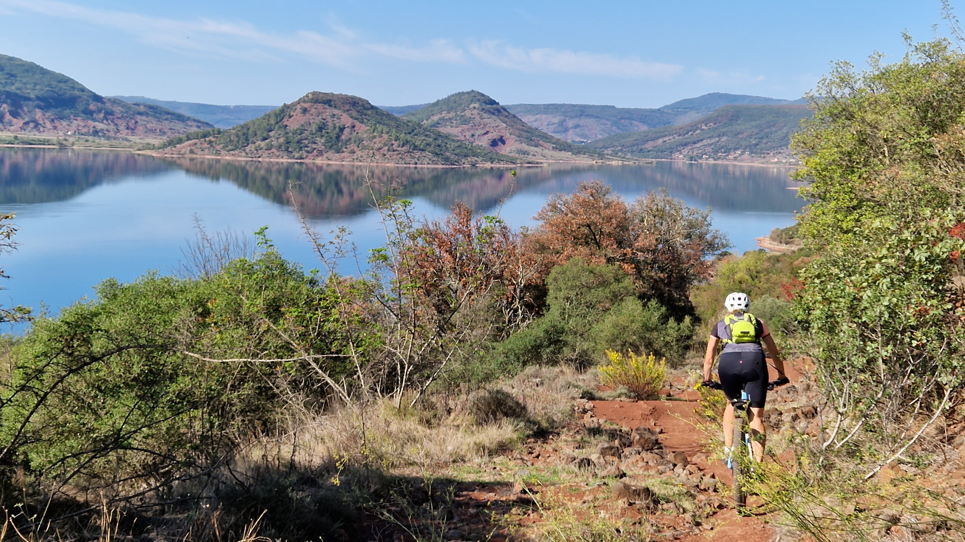 femme à VTT descend un chemin en direction du lac du Salagou